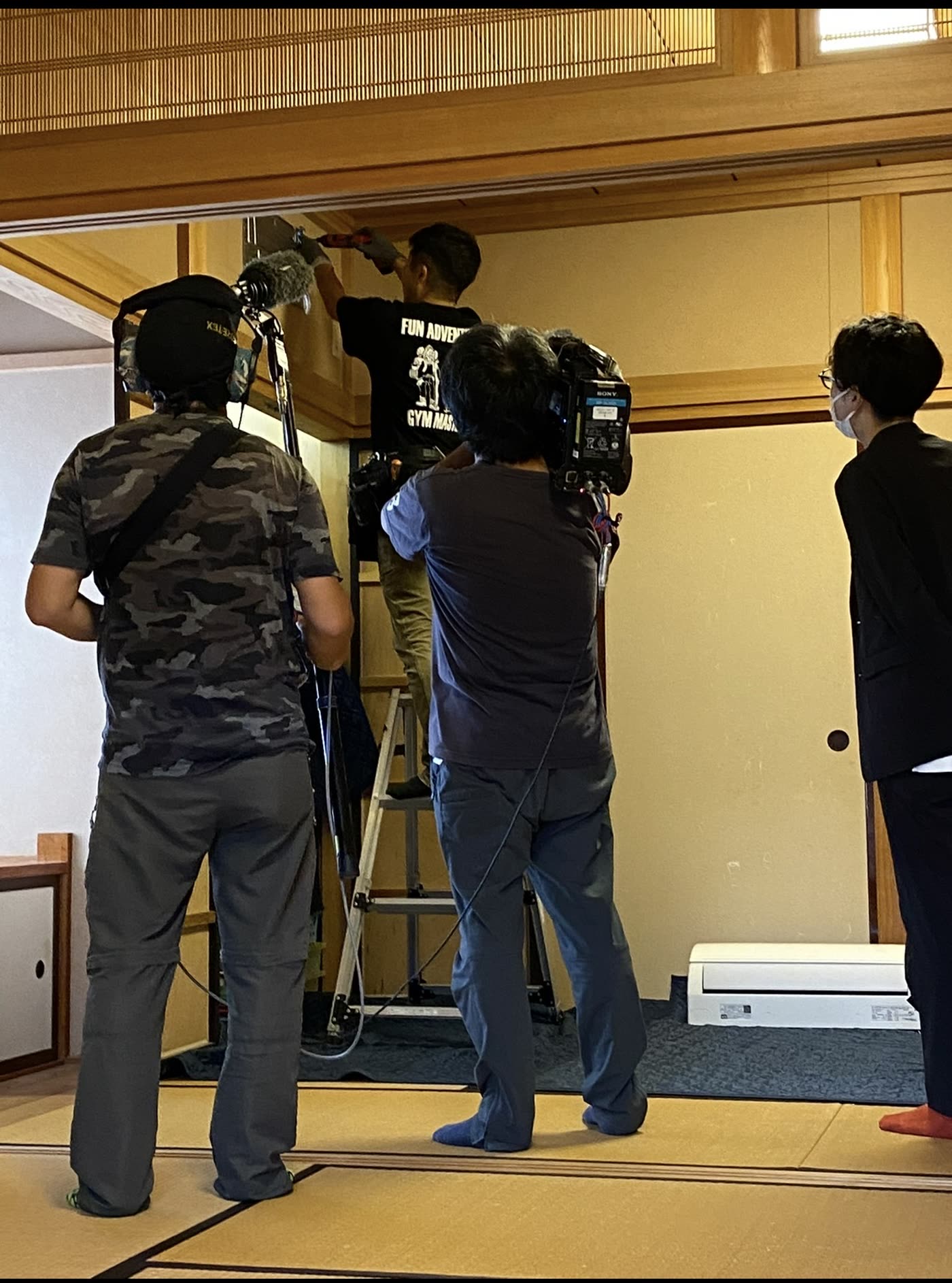 NHKの取材クルーに撮影されながらエアコンを取り付けるひでさん